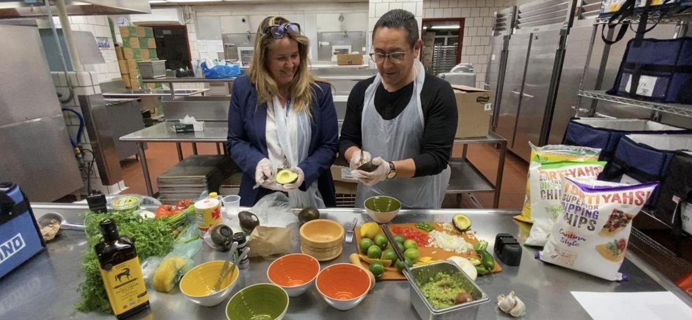 Two adults preparing bowls of fresh food in the school kitchen