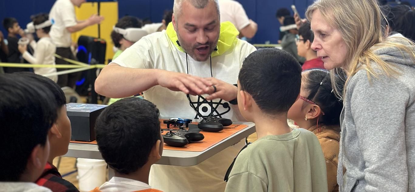Students leaning in to watch a hands-on demonstration on STEM day